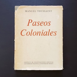 Op de afbeelding: Een vintage boek getiteld "Paseos Coloniales" van Manuel Toussaint. De boekomslag is crèmekleurig met bruine tekst en is uitgegeven door het Instituto de Investigaciones Estéticas, Universidad Nacional Autónoma de México.
