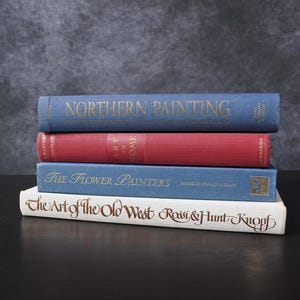 Puede incluir: Una pila de cuatro libros encuadernados con lomos azules y rojos. El libro de arriba tiene el título "Northern Painting". El segundo libro tiene el título "Art in Rome". El tercer libro tiene el título "The Flower Painters". El libro de abajo tiene el título "The Art of the Old West".
