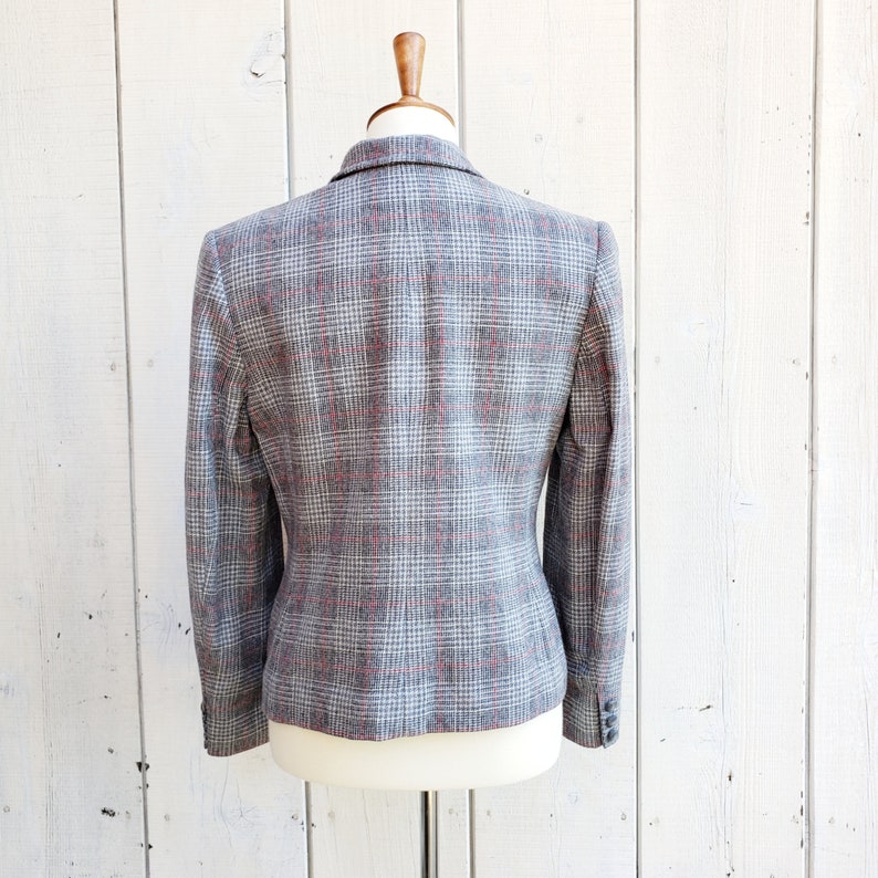 May include: A gray blazer with a red and white plaid pattern. The blazer is on a white mannequin.