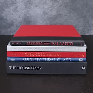 May include: A stack of five hardcover books. The top book is red and black with the text Learning from Palladio. Below it are a light gray book titled The Builders, a red book titled Casa Colombiana, a blue book titled Architectural Glass, and a black book titled The House Book.