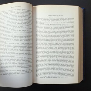 May include: Open book with text on the left page and a section titled "The Enchanted Profile" on the right. The pages are yellowed with age, suggesting an antique or vintage book.