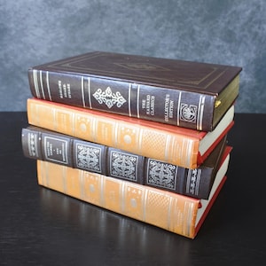 May include: A stack of four hardcover books with brown, red, and orange covers. The books are all part of "The Harvard Classics" collector's edition. The top book has the title "Harlowe  Draxe  Speaks" on the spine.