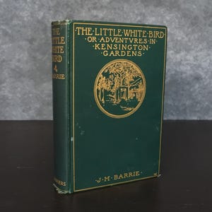May include: A hardcover book titled "The Little White Bird" by J.M. Barrie. The book has a dark green cover with gold lettering and a circular illustration. The spine also features the title and author's name.