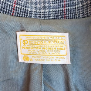 May include: A white label with a yellow border and gold text that reads "WARRANTED TO BE A PENDLETON TRADE MARK REG. U.S.PAT.OFF. PENDLETON WOOLEN MILLS PORTLAND, OREGON 100% VIRGIN WOOL PURE VIRGIN WOOL MADE IN U.S.A."