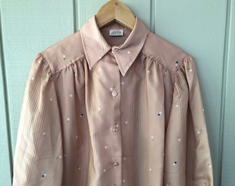 May include: A pale pink long-sleeved blouse with a white collar and button closure. The blouse has a striped pattern with small colorful dots.