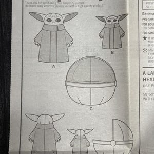 Puede incluir: Patr&oacute;n de costura Simplicity s9432 con ilustraciones de un personaje con orejas grandes y una t&uacute;nica, junto con un objeto esf&eacute;rico y una cuna. El patr&oacute;n incluye el texto "Thank you for purchasing this Simplicity pattern."