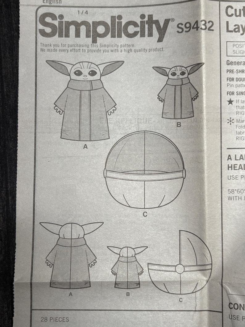 Puede incluir: Patr&oacute;n de costura Simplicity s9432 con ilustraciones de un personaje con orejas grandes y una t&uacute;nica, junto con un objeto esf&eacute;rico y una cuna. El patr&oacute;n incluye el texto "Thank you for purchasing this Simplicity pattern."