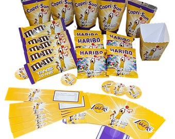 May include: A collection of colorful snack bags and boxes featuring various brands, including M&M's, Haribo, and Capri-Sun. The bags and boxes are arranged on a white surface. The bags feature images of basketball players and the text "YANIS 10 ANS".