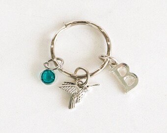 May include: Silver key chain with a hummingbird charm, a teal blue crystal charm, and a letter "B" charm.