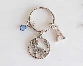 May include: Silver wolf keychain with a blue crystal charm and a silver letter A charm.