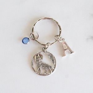 May include: Silver wolf keychain with a blue crystal charm and a silver letter A charm.