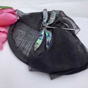 May include: A black hat with a sheer veil and a dragonfly-shaped brooch made of iridescent abalone shell.
