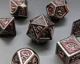 May include: Set of seven black metal dice with red numbers. The dice are in various shapes, including a d20, d12, d10, d8, d6, d4, and a d%.
