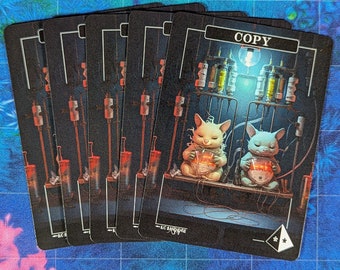 May include: A stack of black cards with a fantasy illustration. The cards feature a detailed image of two cat-like creatures with glowing orbs, surrounded by scientific equipment. The word "COPY" is at the top of the card.