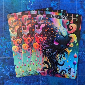 Puede incluir: Tres cartas de intercambio Inkling con una criatura negra y morada con ojos rosas y un fondo de arcoíris. Las cartas tienen un número 21 en blanco y negro en la esquina inferior derecha.