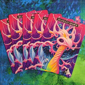 Könnte beinhalten: Fünf Eldrazi Spawn Sammelkarten sind aufgefächert und zeigen eine lebendige Illustration einer Kreatur mit rosa und weißen Merkmalen vor einem lila und blauen Hintergrund. Die Karten haben einen rosa Rand und den Text "ELDRAZI SPAWN".