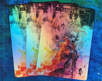May include: Three iridescent playing cards with a watercolor design. The card on top is a "Vampire" card with a watercolor illustration of a person in a red coat standing in front of a castle. The card has a number "1" in the bottom right corner.