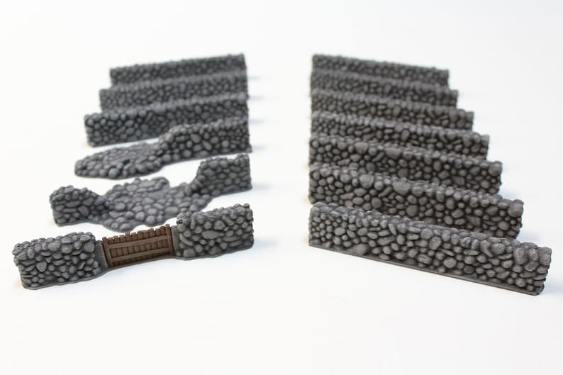 Puede incluir: Colecci&oacute;n de secciones de muro de piedra gris, incluyendo piezas rectas, secciones curvas y una secci&oacute;n con una puerta de madera. Los muros est&aacute;n hechos de peque&ntilde;as piedras redondeadas, para juegos de miniaturas o modelismo.