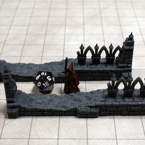 May include: Two gray stone wall sections with arched tops, a miniature figure in a red robe, and a black and iridescent 20-sided die.