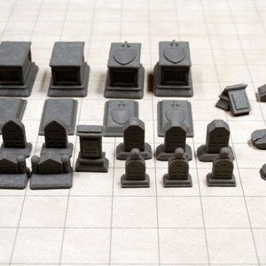 May include: A collection of gray miniature tombstones and mausoleums for tabletop gaming or model building. The set includes various styles and sizes of tombstones, including some with inscriptions.
