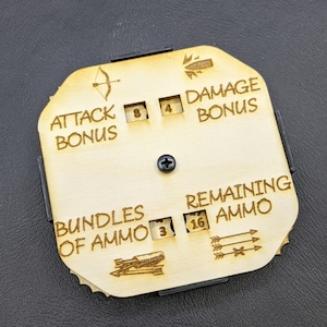 Può includere: Un tracker di gioco in legno con un quadrante circolare e più slot per i dadi. Il tracker ha etichette per "Bonus attacco", "Bonus danno", "Pacchetti di munizioni" e "Munizioni rimanenti".