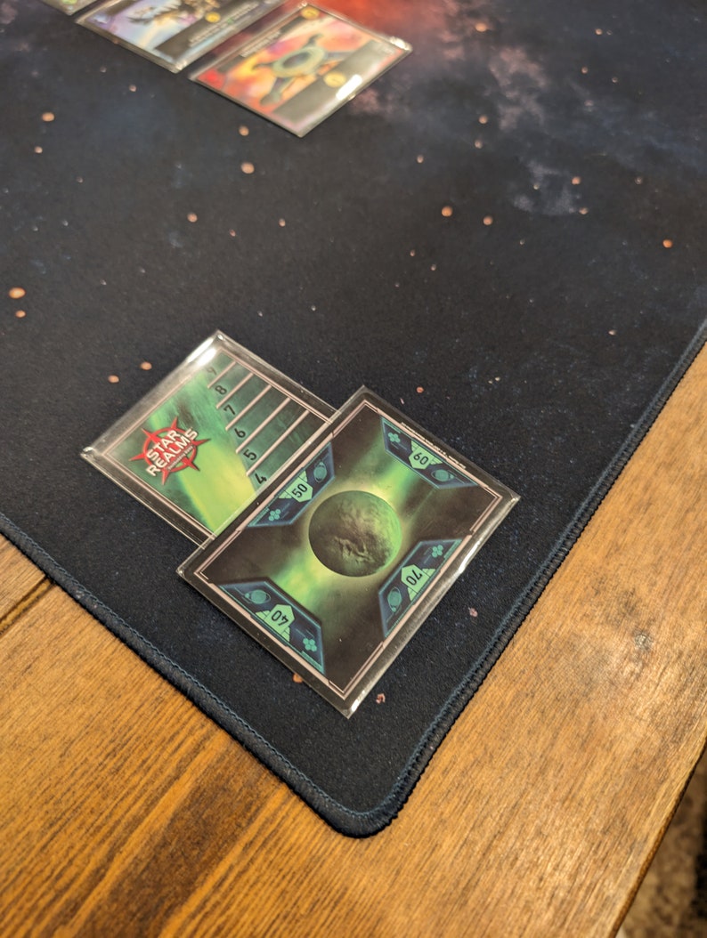 May include: A green and black Star Realms card with a green planet and a number scale from 4 to 8. The card has a black border and a white text box that says "Star Realms".
