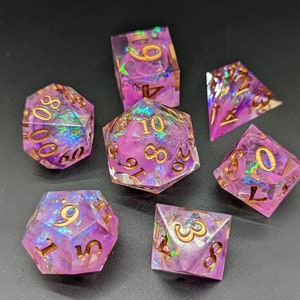 May include: Set of seven iridescent purple dice with gold numbers. The dice are a d4, d6, d8, d10, d%, d12, and d20.