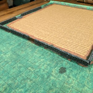 Puede incluir: Un conjunto de terreno para juegos de rol de mesa. El conjunto incluye un mapa de cuadr&iacute;cula verde, un campo marr&oacute;n y un muro de piedra gris. El terreno est&aacute; dise&ntilde;ado para juegos de mesa y wargames en miniatura.