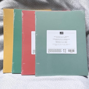 May include: Four stacks of cardstock in yellow, green, coral, and soft green. The cardstock is wrapped in clear plastic. The soft green cardstock has a white label with text. The cardstock is 8.5 x 11 inches.