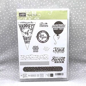 May include: Clear plastic stamp set titled "Sweet Stack" with various phrases and designs for crafting. Includes phrases like "Happiest of Birth Days," "Celebrate Good Times," and "Just as Sweet as Can Be."