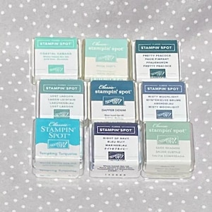May include: Nine Stampin' Spot ink pads in shades like Coastal Cabana, Pool Party, and Tempting Turquoise. Each pad is labelled with its colour name and the Stampin' Up! logo. The ink pads are arranged in a grid pattern.