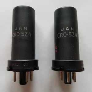 May include: Two black cylindrical electronic components with silver pins and the text "JAN CRC-524" printed on the side.