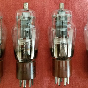 May include: Four vintage vacuum tubes with glass enclosures and metal bases. The tubes are labelled with the numbers "1625" and "625". The bases are labelled with "S.A. 1136".