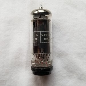 Puede incluir: Un tubo de vacío de vidrio transparente con una base negra y una parte superior plateada. El tubo tiene una etiqueta que dice "CV2127 KB/D SH".