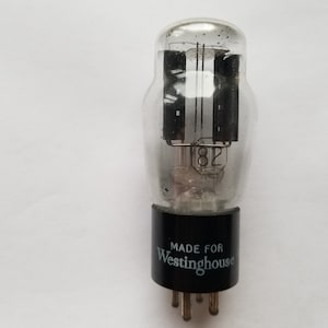 May include: A clear glass vacuum tube with a black base and a silver metal cap. The tube has a label that reads "MADE FOR WESTINGHOUSE".