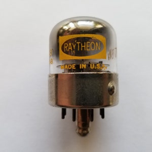 Pode incluir: Um tubo de vácuo Raytheon prateado com o texto "MADE IN U.S.A." e "W67" impresso no vidro.