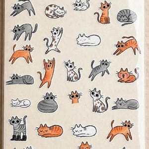 May include: A spiral-bound notebook featuring a collection of small, hand-drawn cat stickers in various poses and colors, including orange, gray, white, and spotted patterns. The bottom of the page displays the text Waverly Snow with small stars.