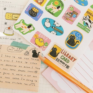 May include: A to-do list with a yellow background and black text. The list includes items like "add new things on Etsy" and "organize my room". There are also several colorful stickers with illustrations of animals, food, and other objects.