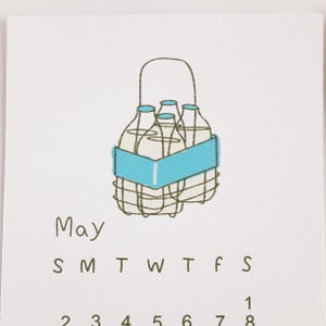 May include: A calendar for the month of May with a hand-drawn illustration of a milk crate with four milk bottles inside. The text "May" is written in brown below the illustration. The days of the week are abbreviated as "S M T W T F S" and the numbers 1 through 8 are written below the days of the week.