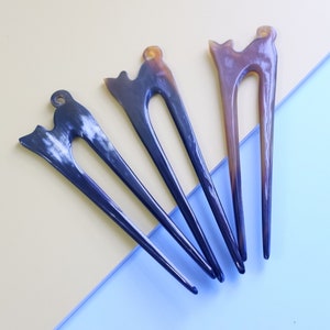 May include: Four hair sticks with a cat design. Two are brown and two are black with white swirls.