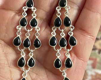 May include: A pair of dangle earrings with multiple black teardrop-shaped stones and silver accents.