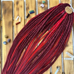 May include: Burgundy and red synthetic dreadlocks with a tag that says "Handmade with love".