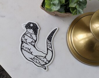 May include: Black and white line art sticker of an otter with a detailed pattern on its body. The otter is curled up with its tail tucked under its body.