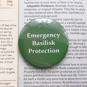 Puede incluir: Un botón verde con el texto "Emergency Basilisk Protection" en letras blancas. El botón es circular, plano y tiene un acabado brillante.