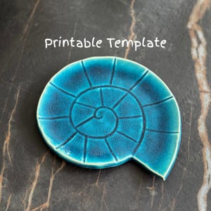 May include: A teal ceramic plate in a nautilus shell design. The plate has a spiral pattern with dark blue lines and the text "Printable Template" in white.