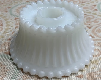 Könnte beinhalten: Weißer Kerzenhalter aus Glas mit einem perlenbesetzten Rand und einem geriffelten Sockel.