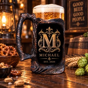May include: A dark, textured beer mug with a wood-like finish and a large handle. The front features a gold-colored ornate letter M, the name MICHAEL, and the text EST. 2020. The mug is filled with golden beer topped with a thick white foam head.