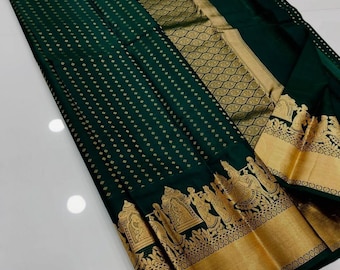 May include: A dark green textile with gold accents. The fabric features a repeating dot pattern and ornate gold borders with detailed figures. The design suggests a traditional garment, possibly a saree or similar formal wear.