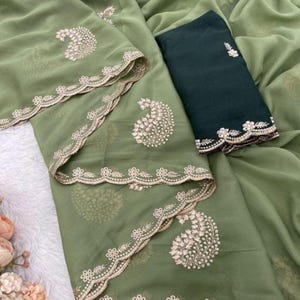 Puede incluir: Un conjunto verde oliva con bordados detallados. El conjunto incluye una parte superior y una parte inferior verde oscuro contrastante. La parte superior tiene un dise&ntilde;o de cachemira y un borde festoneado. La tela parece transparente y ligera, adecuada para climas c&aacute;lidos.