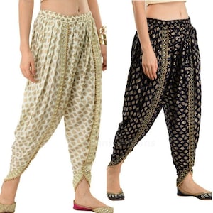 Puede incluir: Dos pares de pantalones impresos con detalles dorados. Un par es blanco con estampado dorado y el otro es negro con estampado dorado.